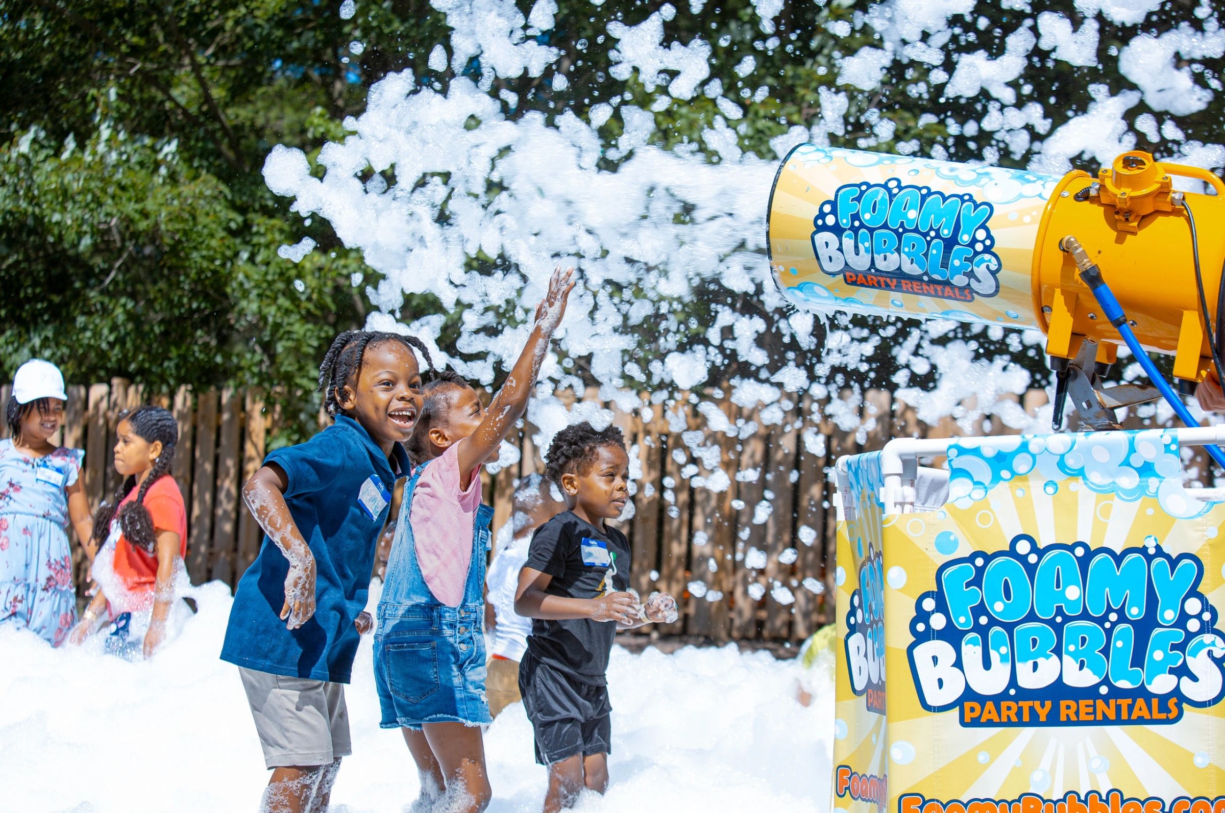 Children reaching toward a foam cannon at a family event